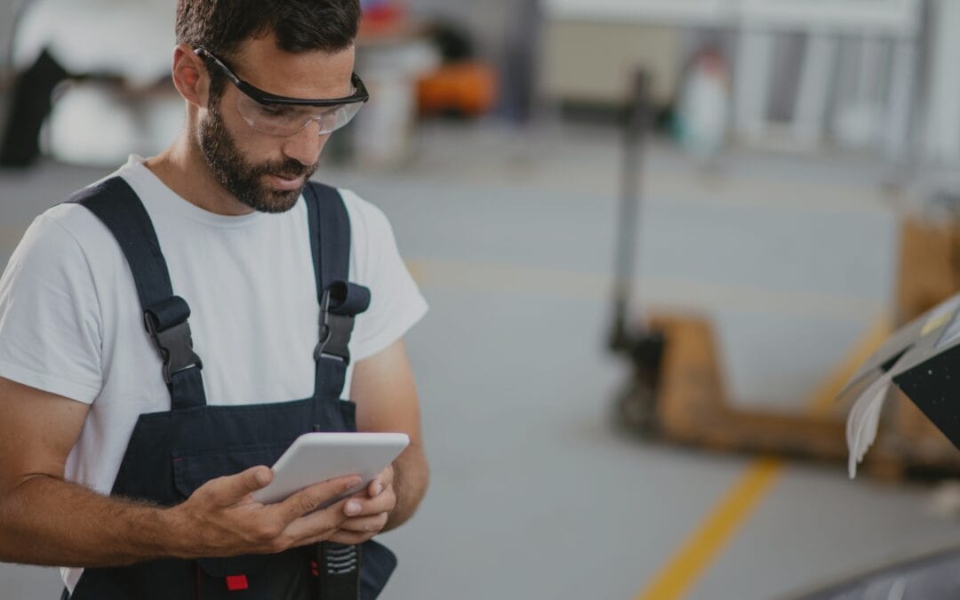 A factory worker in overalls reviewing digital work instructions on a tablet, ensuring accuracy and efficiency in the production process.