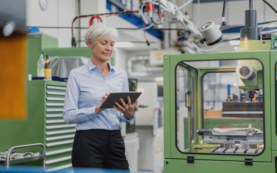 A senior manufacturing manager using a tablet to monitor traceability processes in a modern production facility.