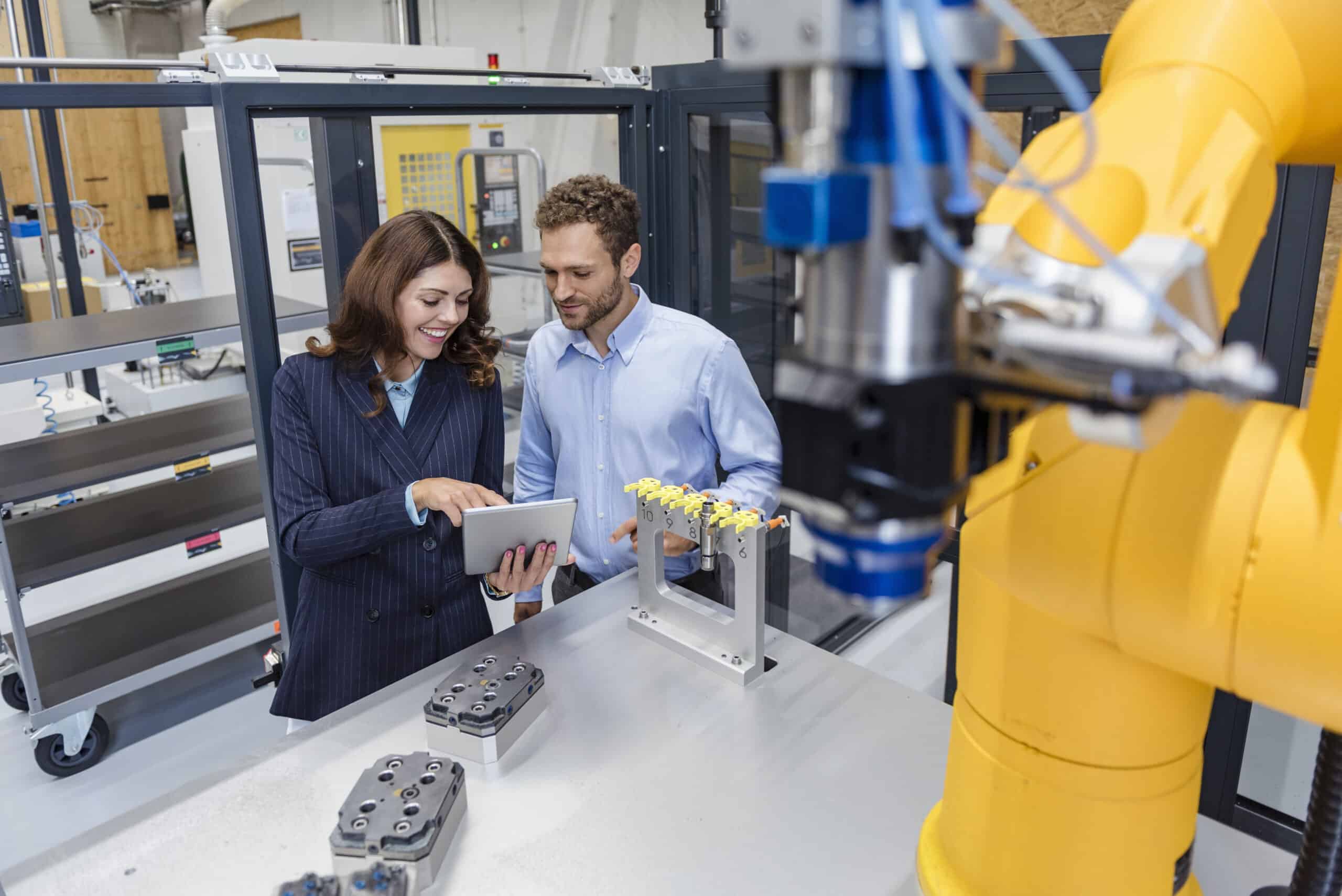 Colleagues in high tech company controlling industrial robots, using manufacturing execution system