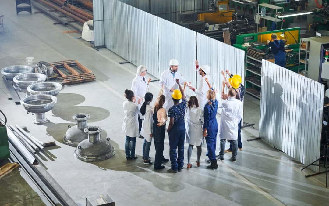 Full length portrait of mature factory managers talking to group of angry workers during meeting in industrial workshop,